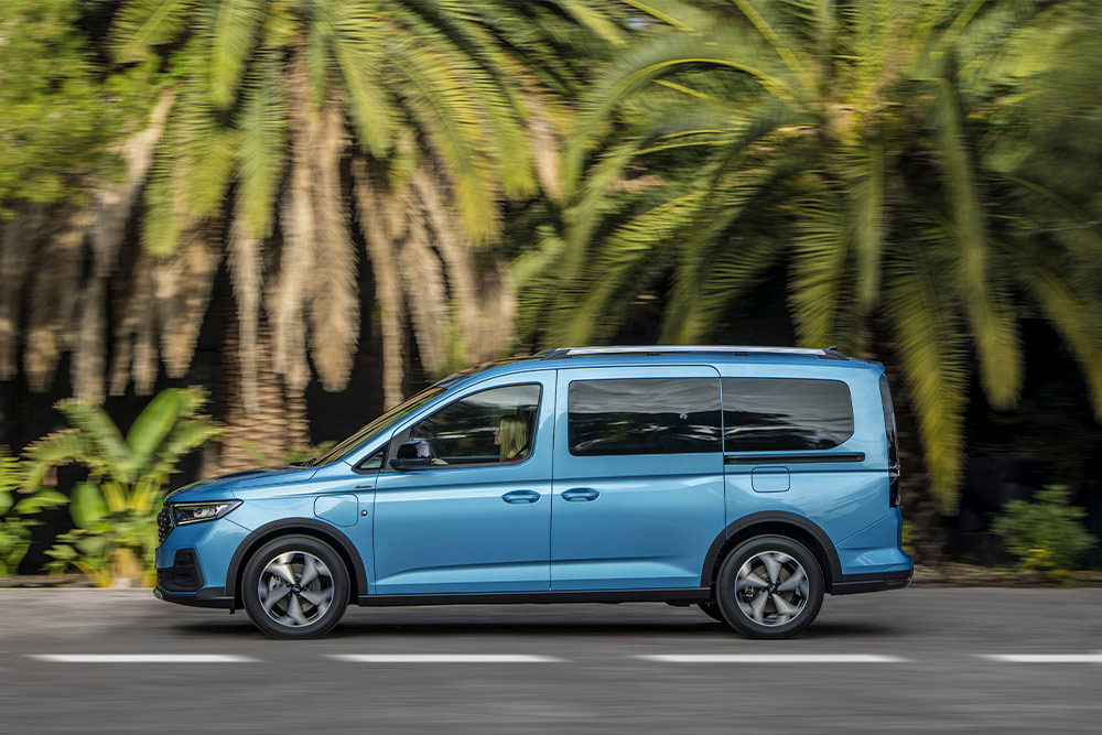 Un fourgon hybride rechargeable Ford Tourneo Connect bleu garé dans une rue.