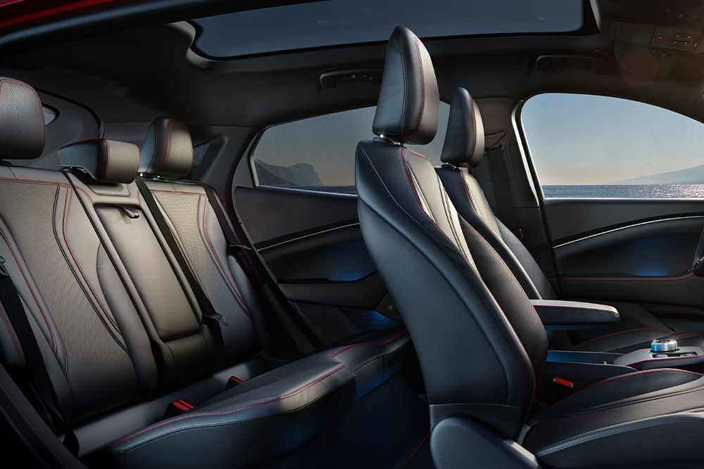 Intérieur de la Ford Mustang Mach-E, avec ses cinq sièges confortables à finition en matériau noir avec des coutures rouges.