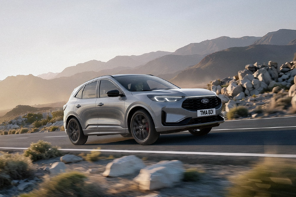 Ford Kuga gris traversant un paysage de montagne rocailleux.