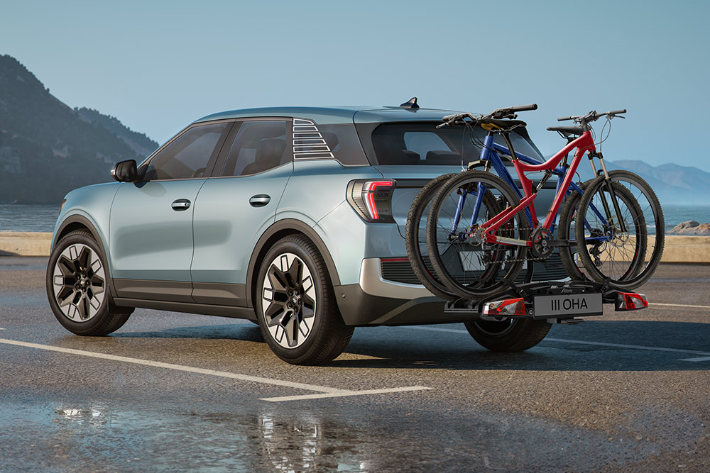 Ford Explorer de couleur bleue circulant sur un chemin de terre, avec barres de toit, porte-vélos et deux vélos montés sur le toit.