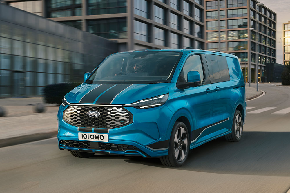 Un fourgon Ford E-Transit Custom Sport double cabine bleu roule dans la rue d'une ville.