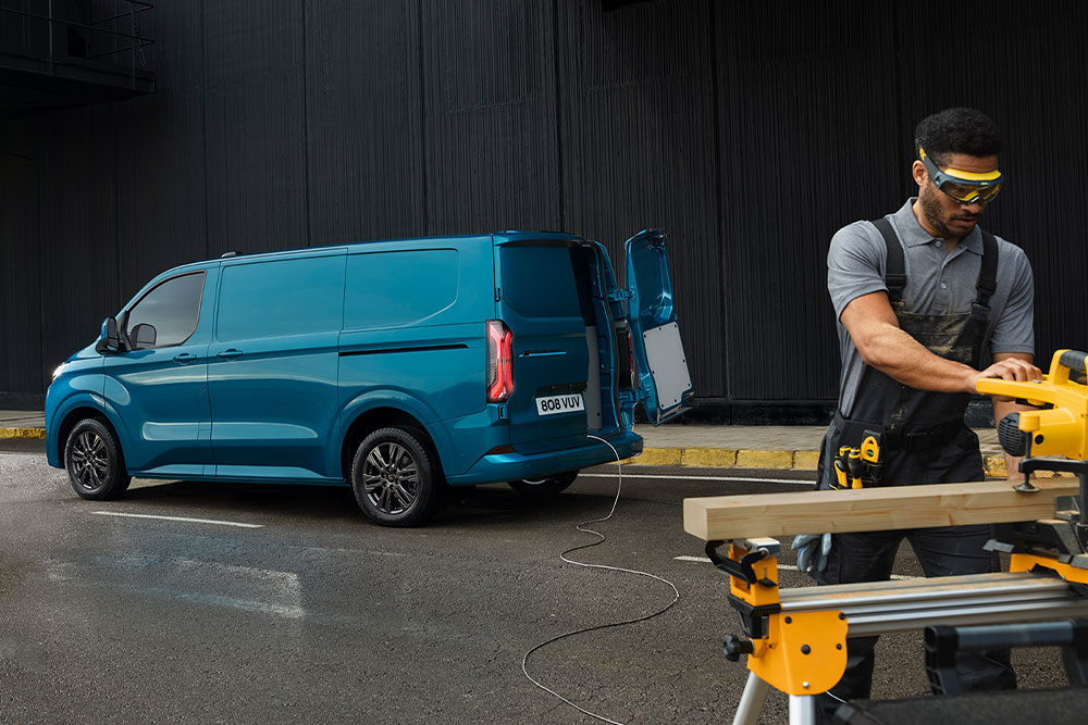 Fourgon électrique Ford E-Transit Custom bleu et une personne utilisant des outils électriques.