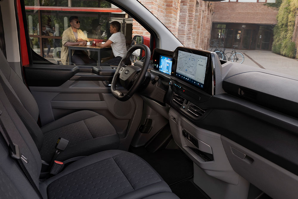 Une personne assise sur le siège conducteur d'un Ford Transit Custom rouge.