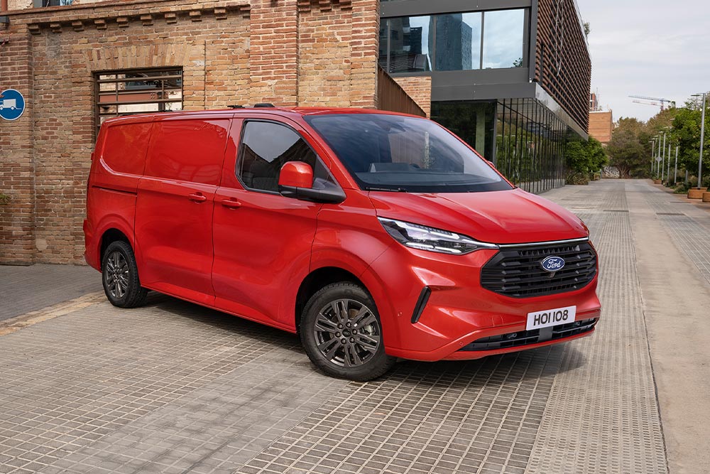 Un livreur charge des colis dans un Ford Transit Custom rouge.