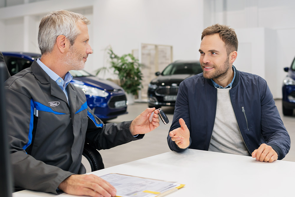 Un conseiller Ford remet les clés à un client tout en lui présentant la gamme d'options de financement Ford.
