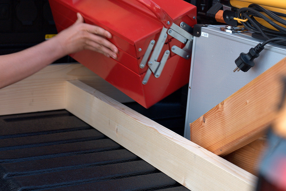 Gros plan sur une personne plaçant une boîte à outils rouge sur la plateforme de chargement d’un Ford Ranger.