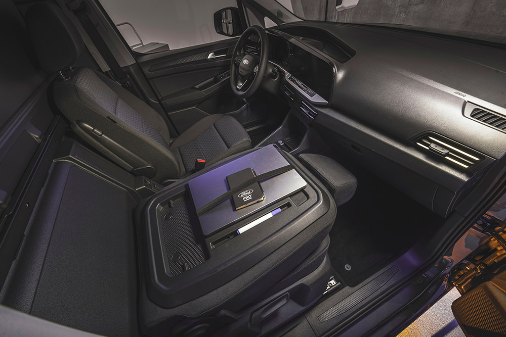 Habitacle du Ford Transit Connect montrant le tableau de bord, les sièges, un ordinateur portable et un téléphone sur la console centrale.