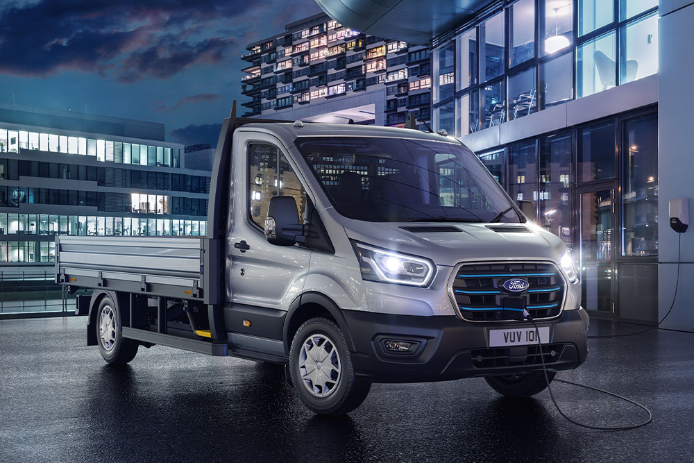 Ford Transit Châssis-Cabine argenté stationné devant un bâtiment moderne, de nuit.
