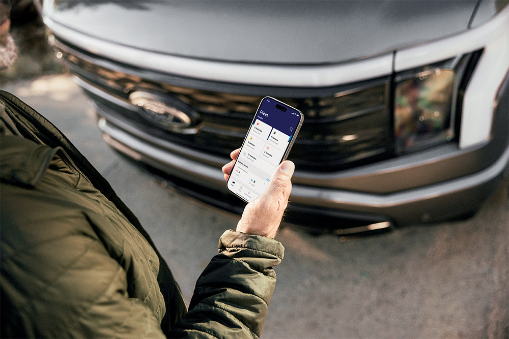 Un homme consultant son smartphone devant un Ford Ranger.
