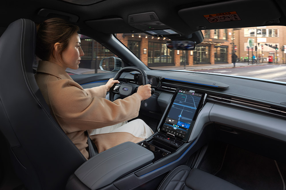 Personne conduisant un véhicule Ford, avec le grand écran tactile central affichant la navigation.
