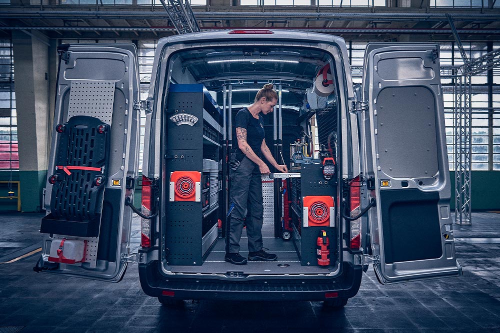 Technicien à l'arrière d'une camionnette Ford, vérifiant les données sur son ordinateur portable.