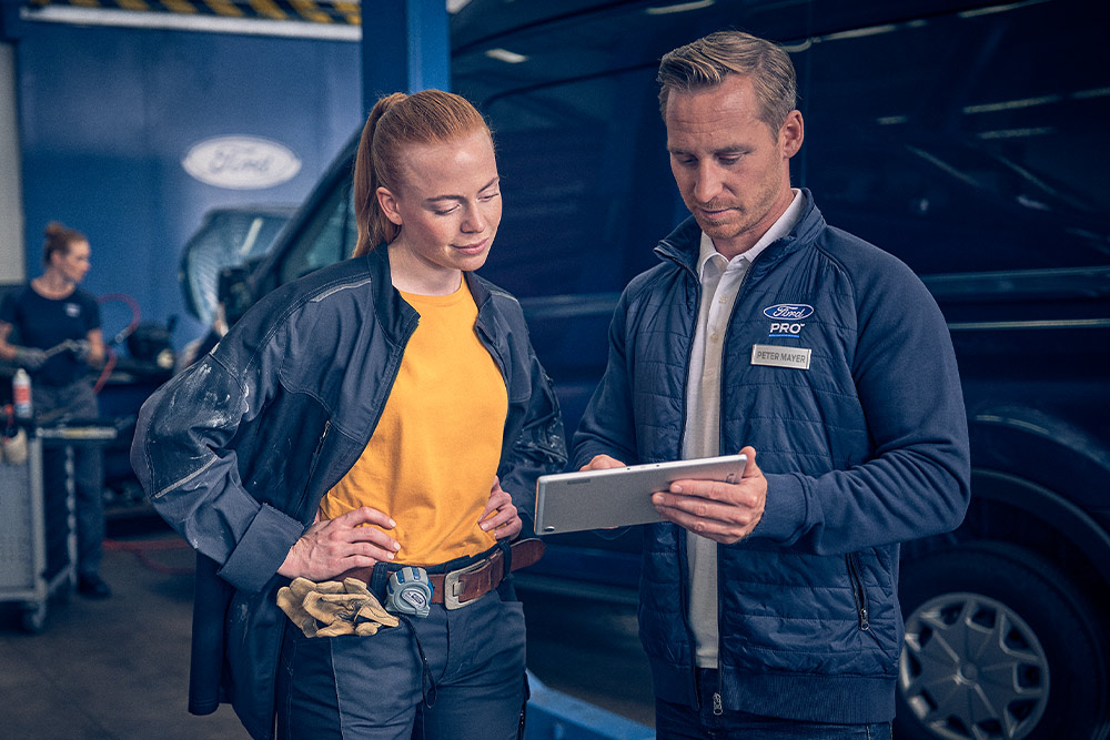 Technicien Ford et gestionnaire de flotte examinant les données sur une tablette dans un garage.